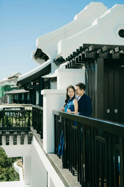 a couple standing together outside of a black balcony