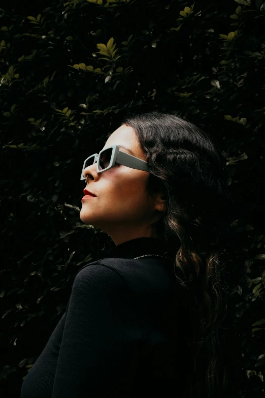 woman in dark wearing sunglasses next to trees