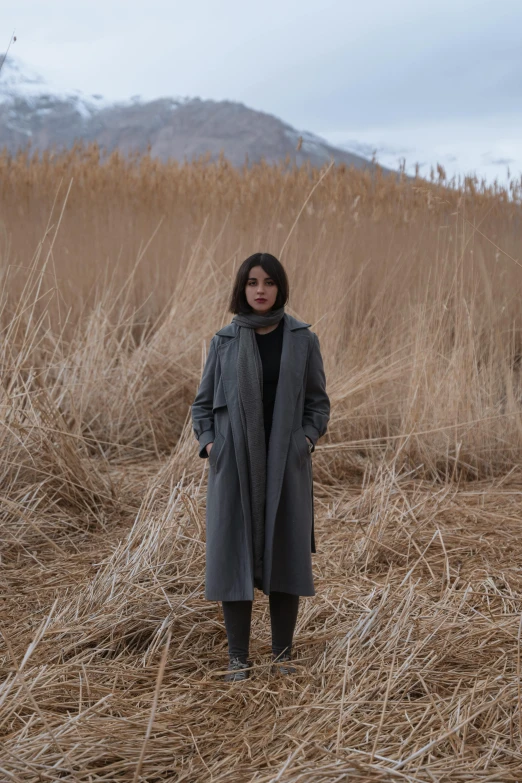 a woman standing in a field with tall dry grasses