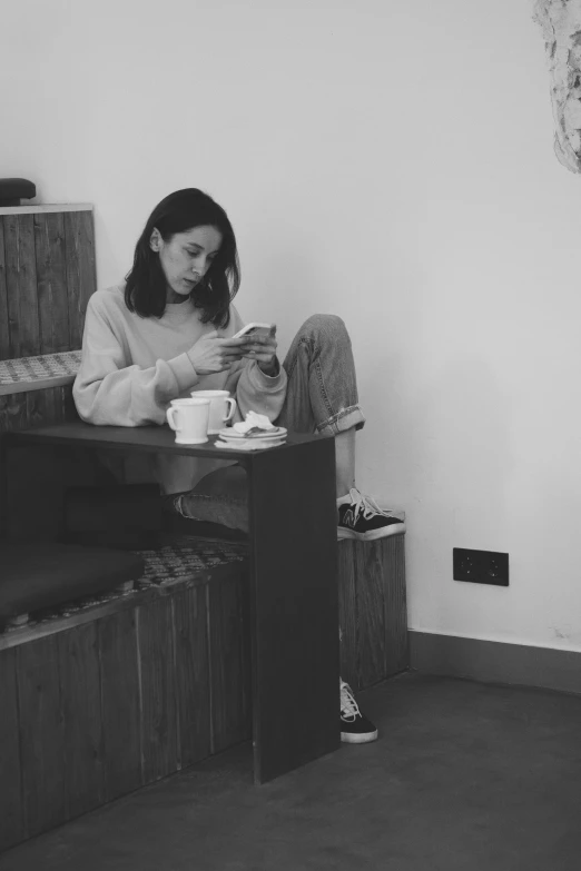 a black and white po of a young woman sitting on the floor with a cup of coffee