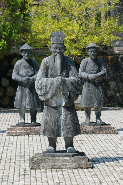 three statues of men standing around each other on a small piece of cement