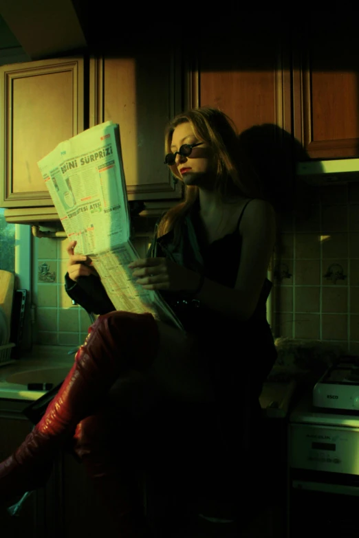 woman sitting in kitchen reading newspaper under light