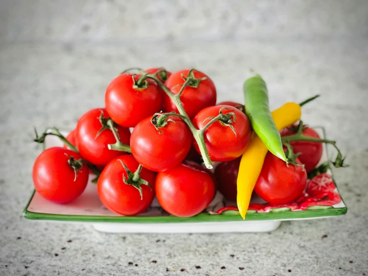 a plate full of small red tomatoes on the counter