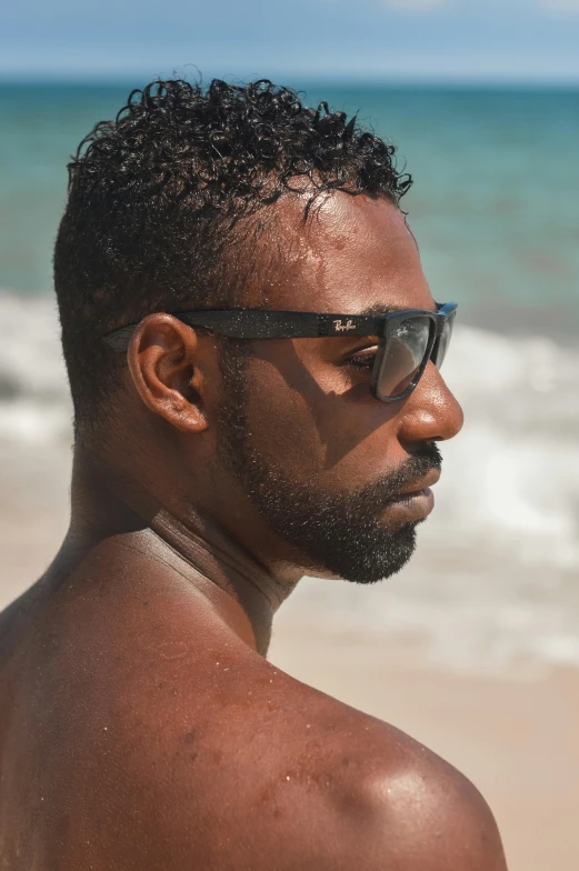 a man wearing shades on the beach with a blurry background