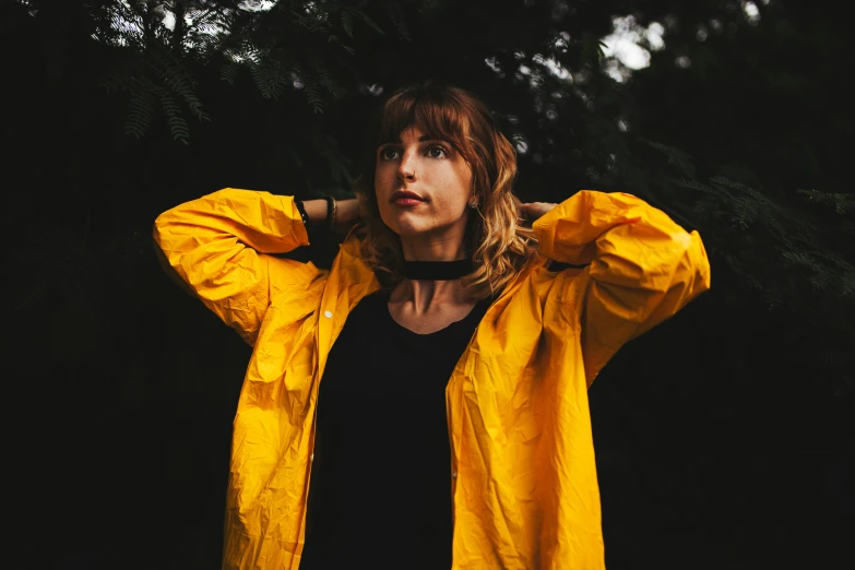 a young woman in yellow jacket standing in dark area