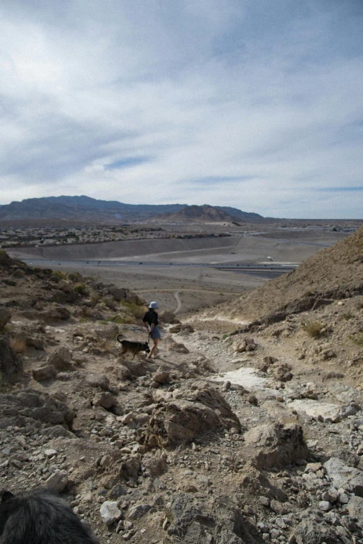 two people hiking on rocks next to a body of water