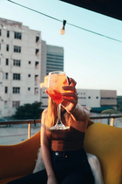 a woman holding up a pink drink in a tall glass