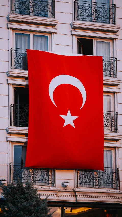 a large turkish flag with the stars and crescent on it in front of a building