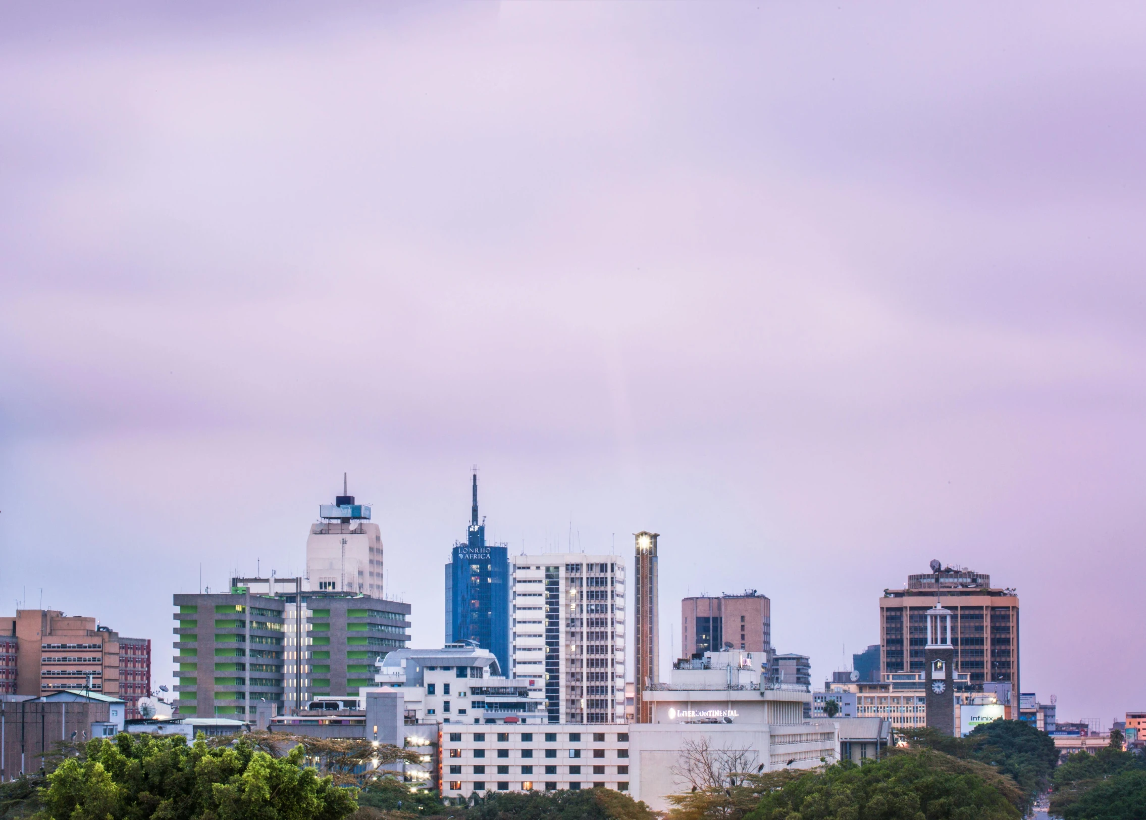 several city skylines are seen against a pink cloud filled sky