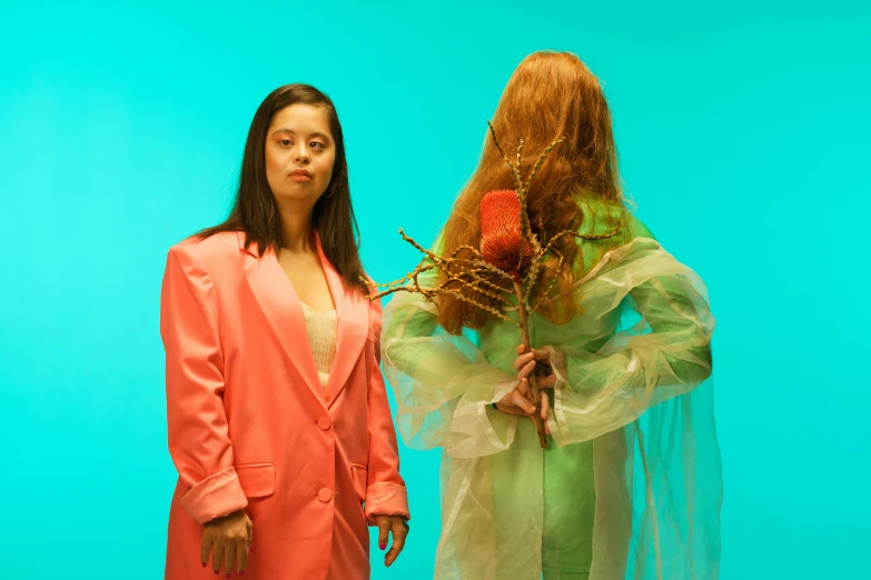 a young woman holds a small bouquet next to a woman in a tulle