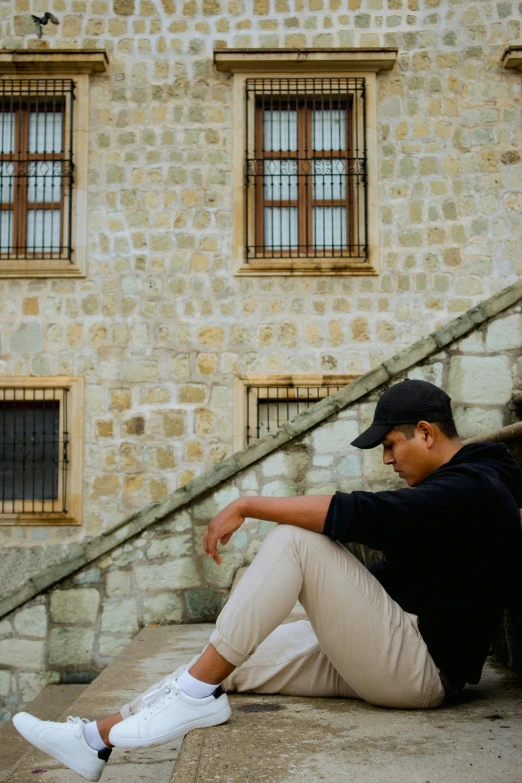 a man sitting against some stairs and looking at his cellphone