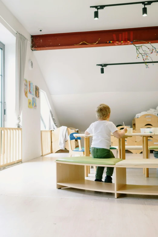 a little boy playing with toy wooden furniture in a room