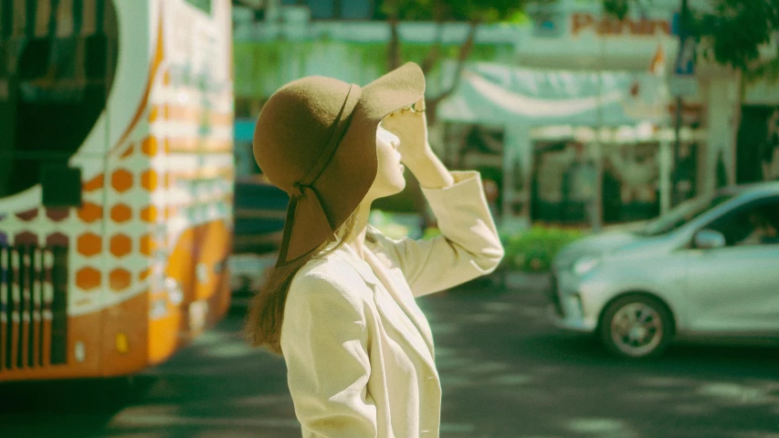 a woman wearing a hat walks down the street