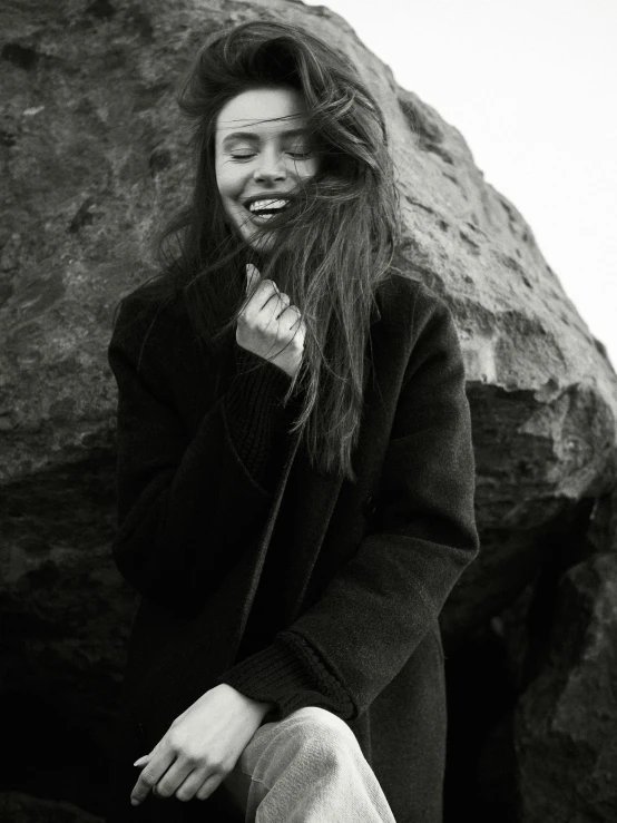 a black and white po of a woman sitting on the rocks