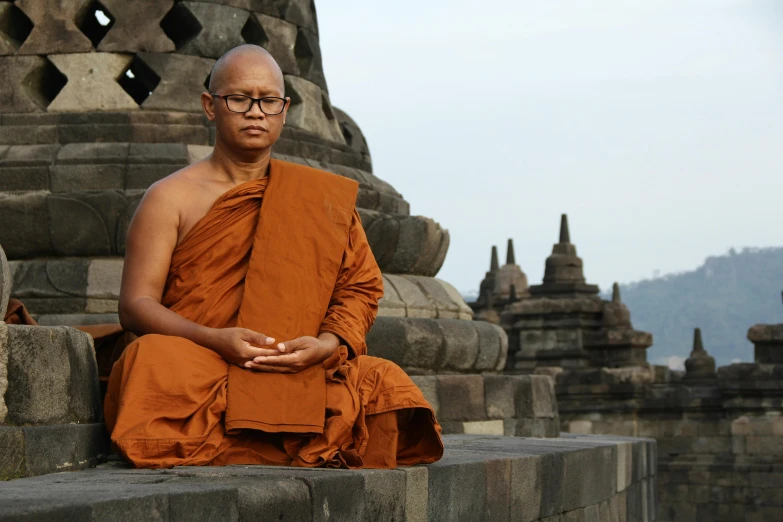 a young monk sitting on top of a stone wall