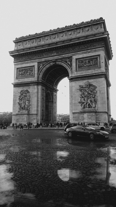 a group of people walking over a dle in front of the arc de trioe