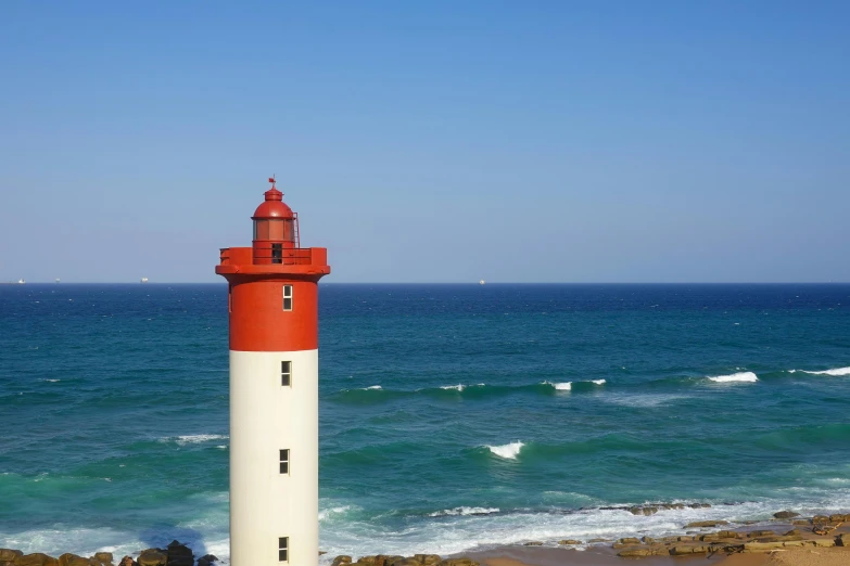 a red and white lighthouse sitting on top of rocks