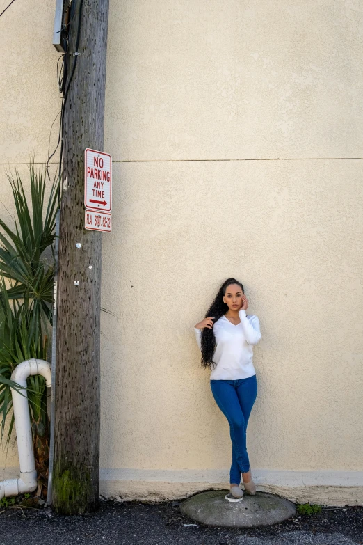 a woman leaning against a building while talking on a phone