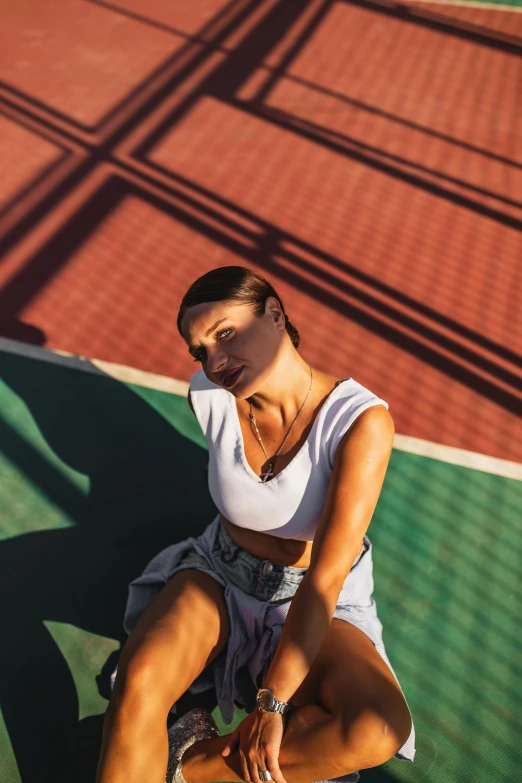 there is a woman sitting on the ground in tennis court