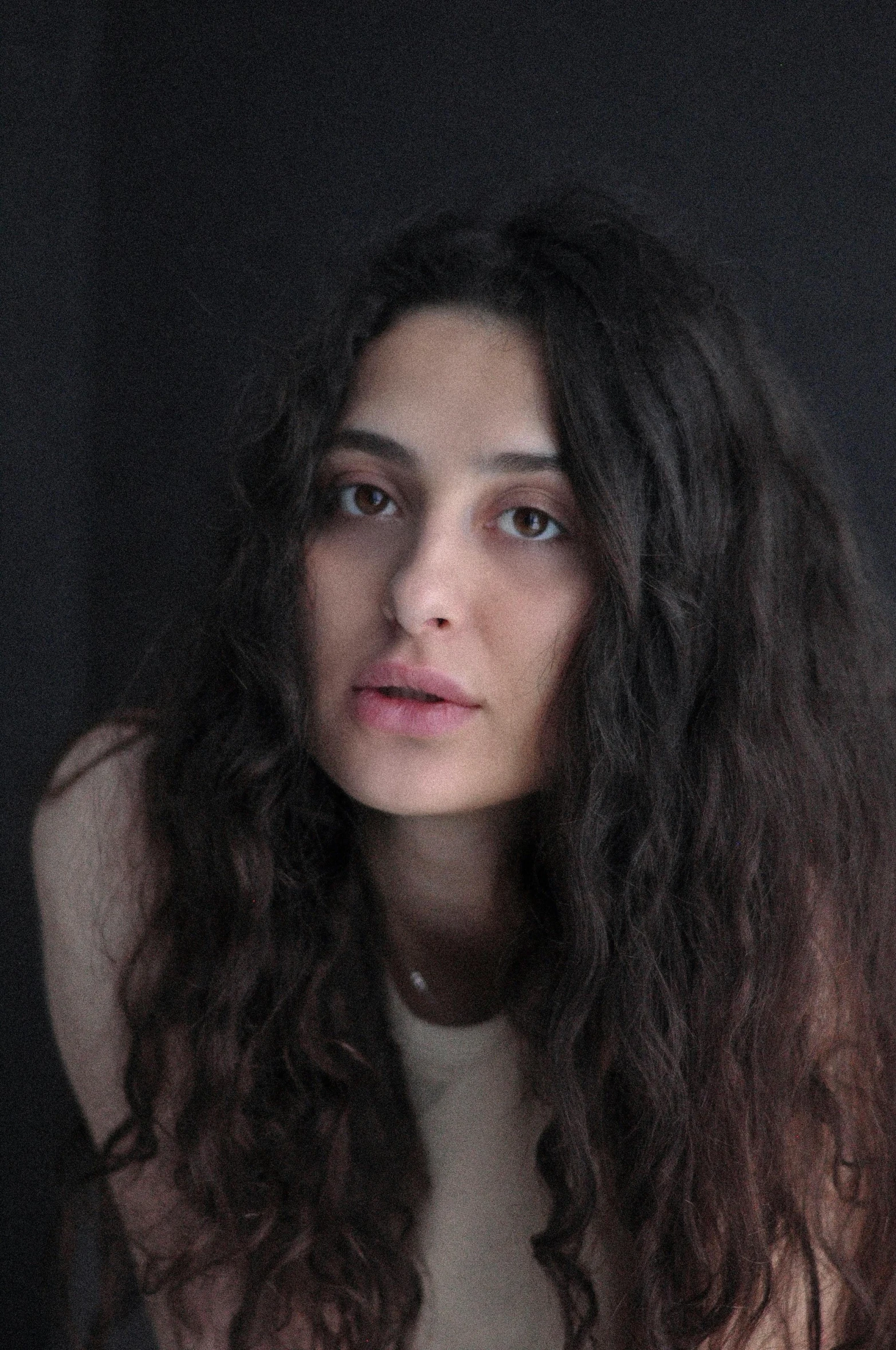 a woman with long curly hair and one eye closed