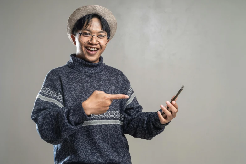 an asian man is holding his phone and smiling