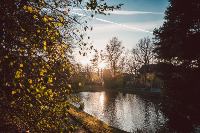 the sun is rising over a lake with trees