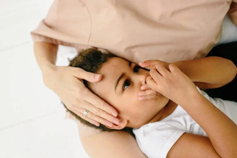 an adult holding the hand of a child on top of their head