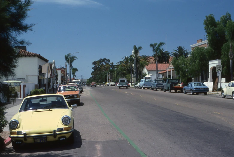 cars on a street lined with palm trees and houses