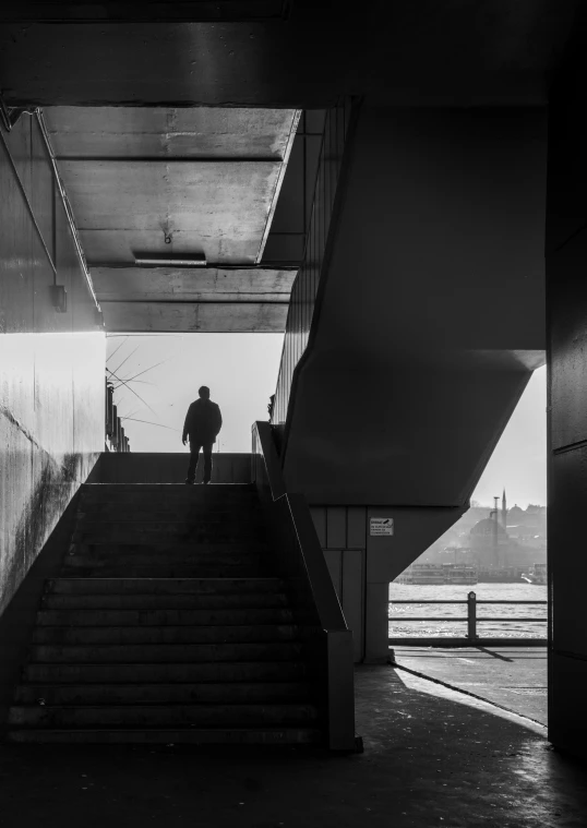 a man in silhouette on stairs of the escalator at a city pier