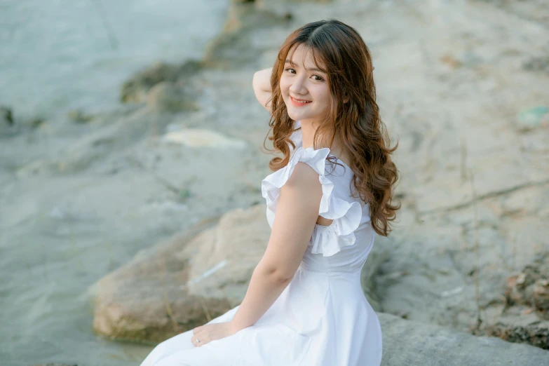 a girl in white is sitting on rocks