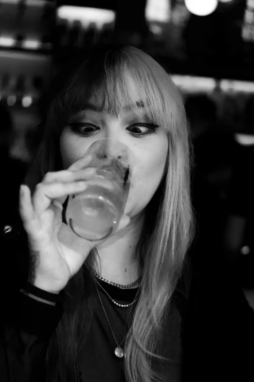 a woman drinking from a glass on a table