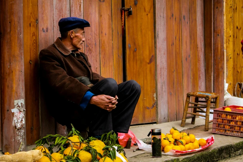 an older man sitting on the step with a lot of lemons