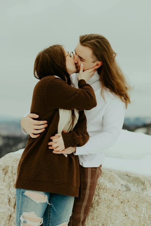 two people kissing each other on top of a mountain