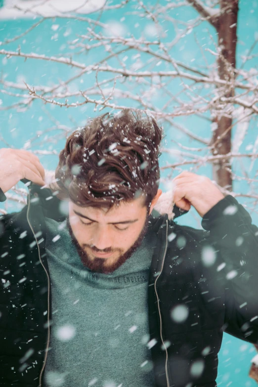 a man with his hand on his hair standing in front of trees