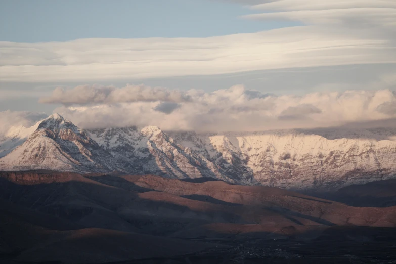 a snowy mountain covered in clouds on a partly cloudy day