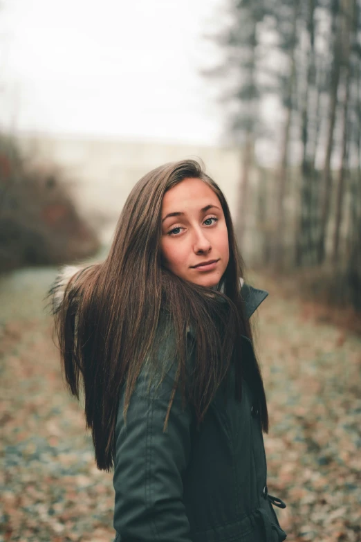 a  with long hair posing in front of trees