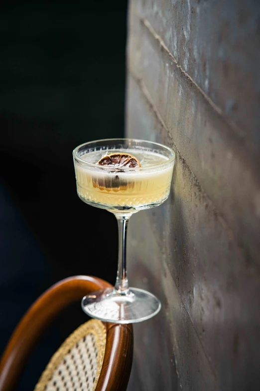 a beverage on the edge of a chair near a brick wall