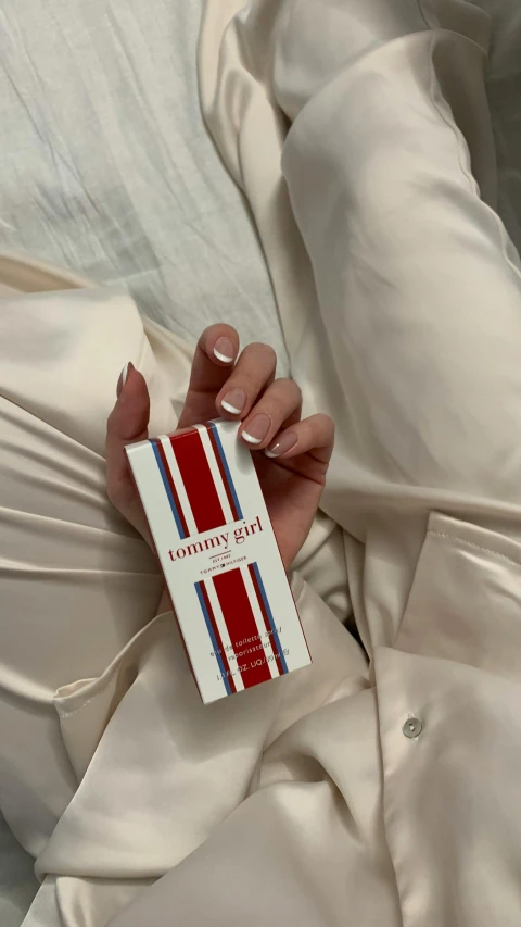 a woman is holding an unused carton of lipstick in her hands