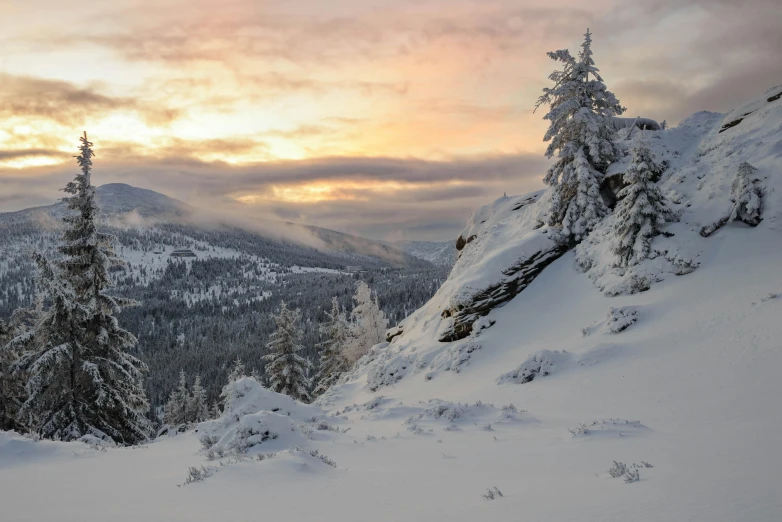 a cloudy sunrise seen over a snow - covered mountain