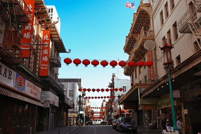 the street is lined with chinese lanterns hanging down the sides of buildings