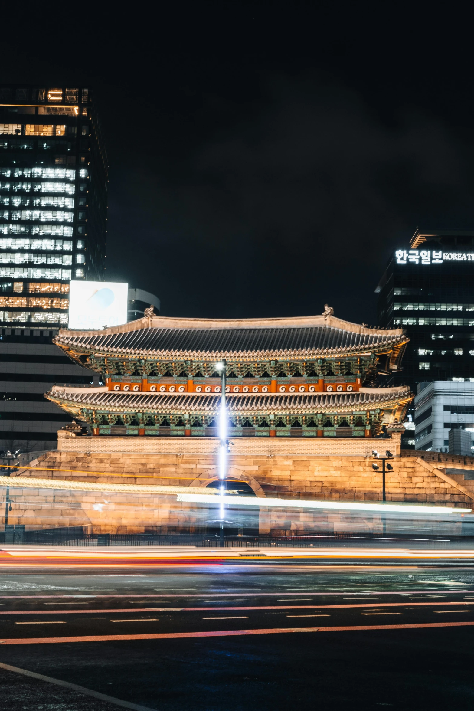 two buildings near one another at night with lights from cars