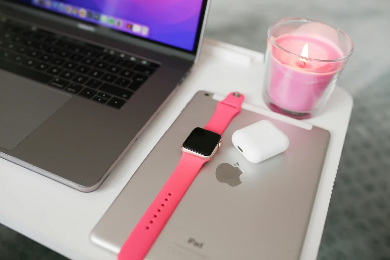 the apple watch, small candle, and smart phone are beside an ipod