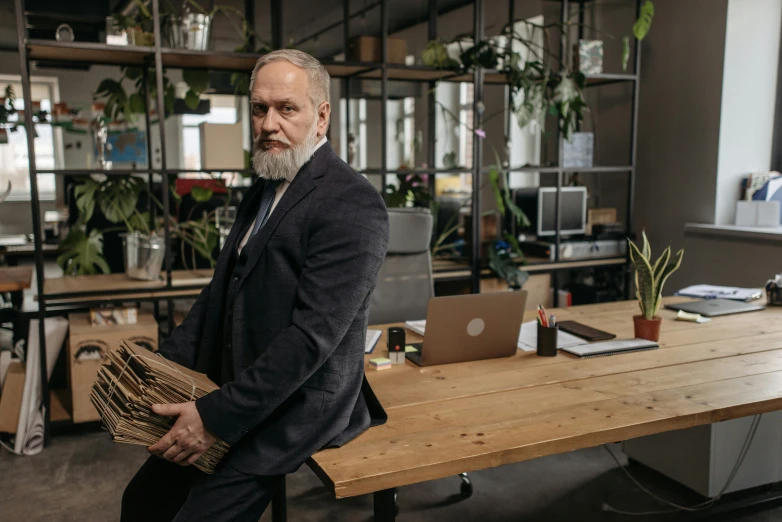 man standing next to a table holding papers