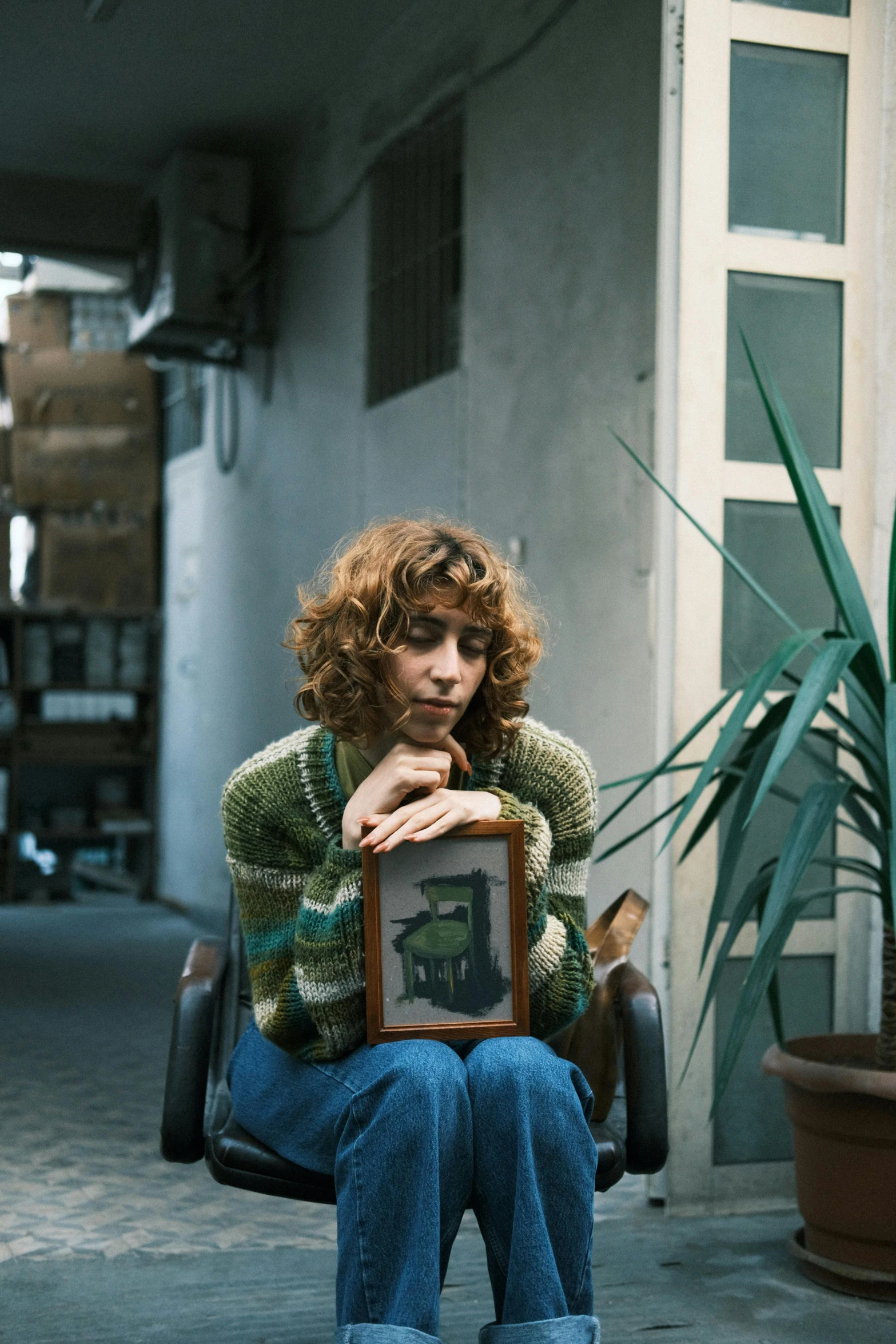 a woman sitting on top of a chair holding a framed piece