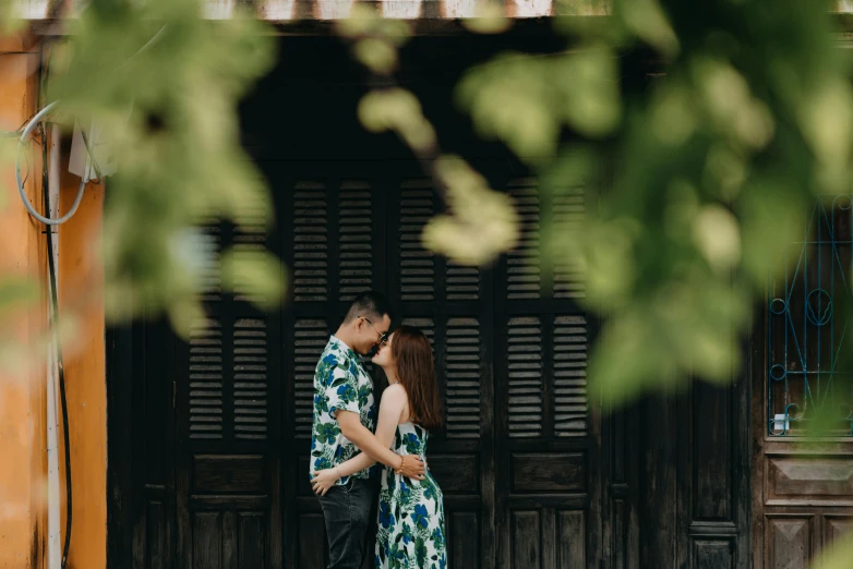 two people in front of a building with some plants