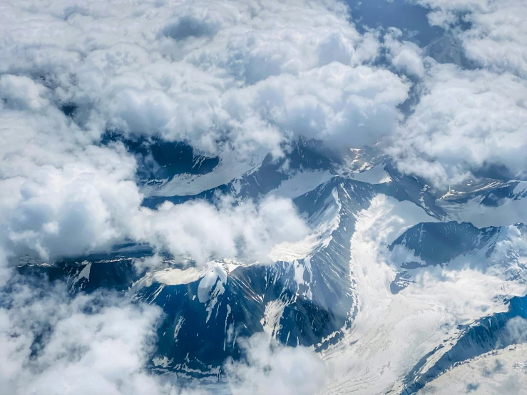 view of mountains covered in clouds from an airplane window