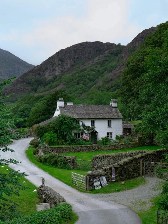 the road and cottage are surrounded by mountains