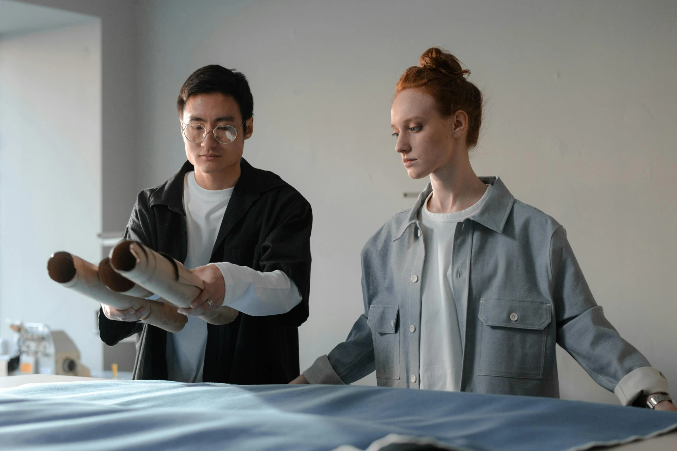 two people in a room, one holding rolled up a large sheet