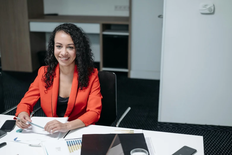 a woman in an orange jacket is sitting at a table