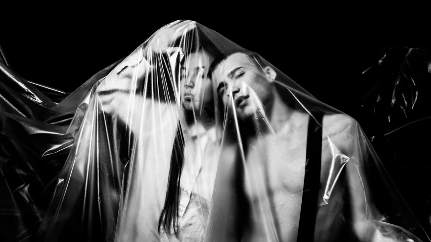 two people wrapped in plastic in black and white
